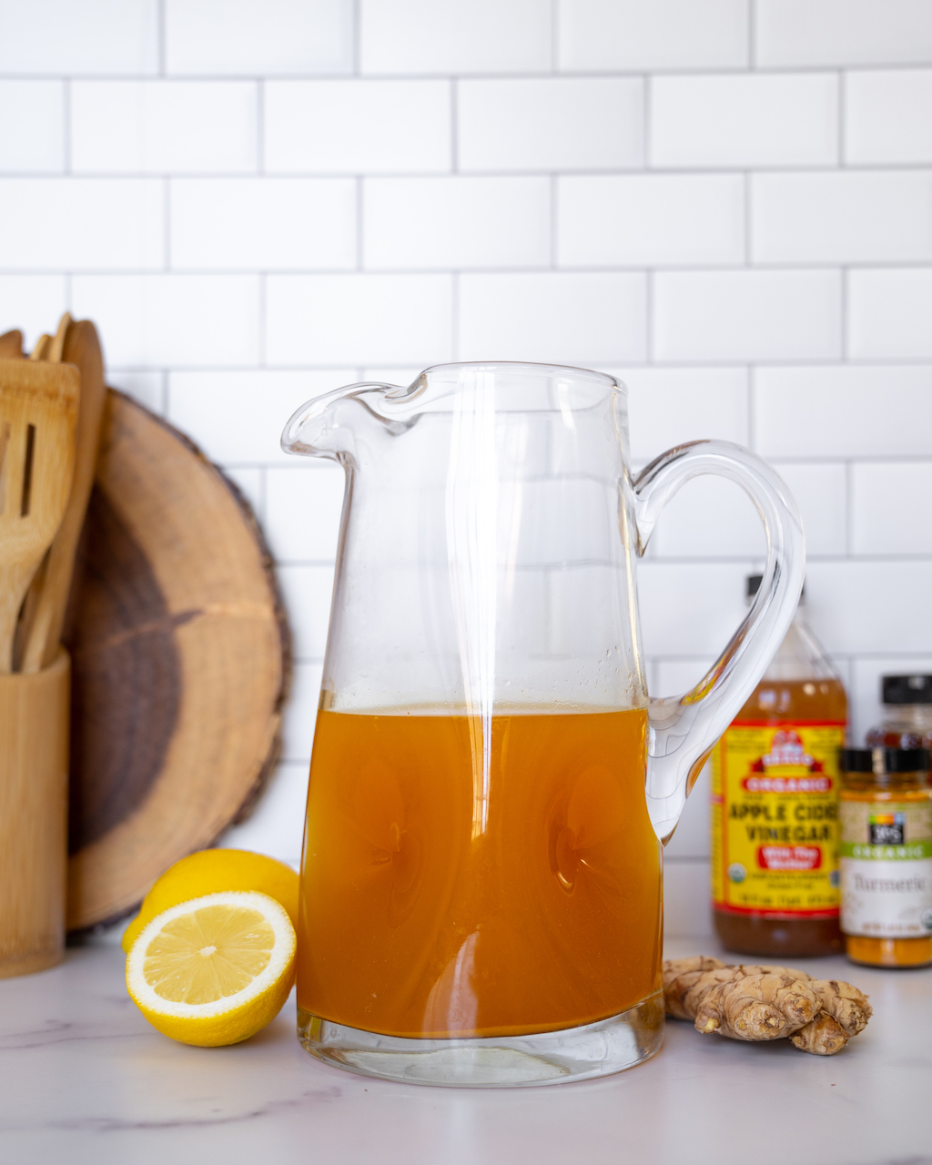 Pitcher of Super Youth Apple Cider Vinegar Detox Recipe with ingredients in the background