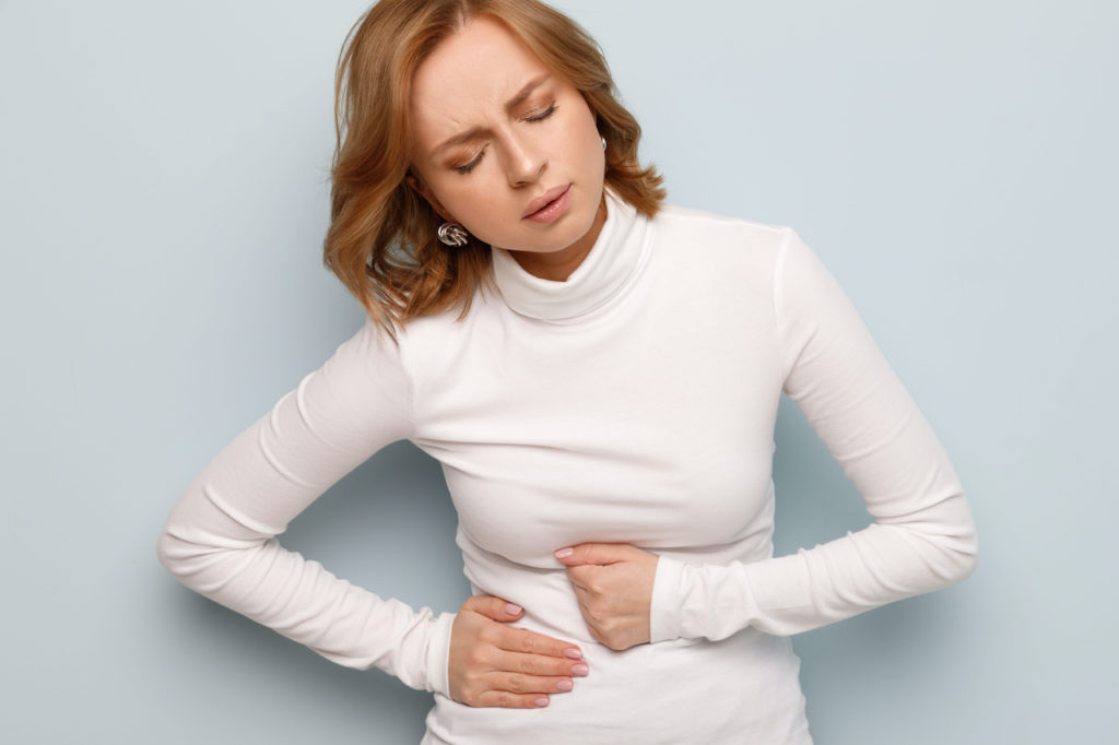 Woman holding her stomach trying to get rid of bloating fast.