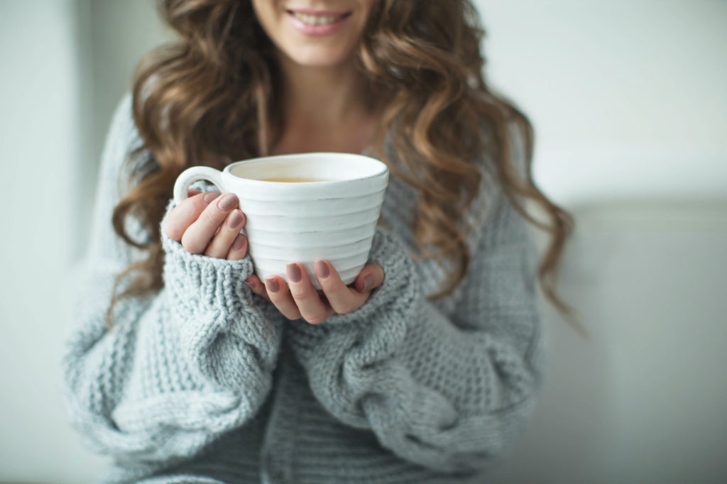 A woman drinking Detox tea from a large mug.