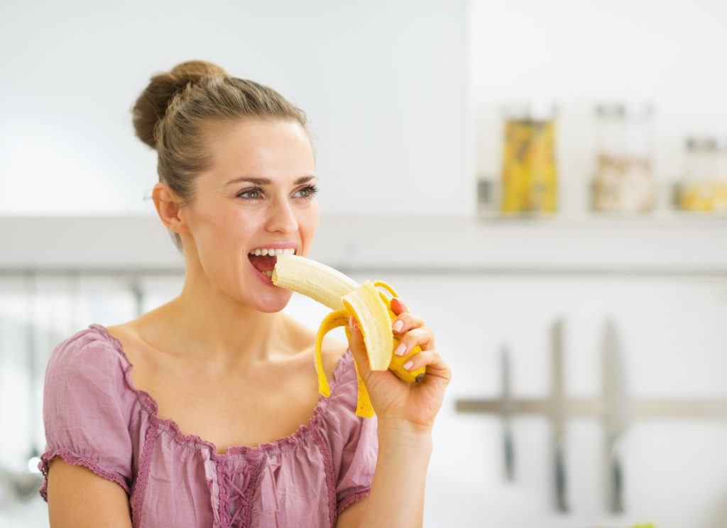 Woman eating a banana for the potassium to get rid of bloating fast