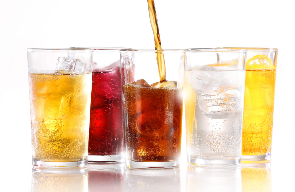 Carbonated drinks on a table with white background. Avoiding carbonated drinks can help you get rid of bloating fast.