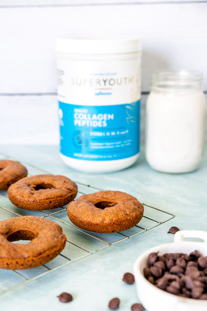 Healthy Zucchini Baked Donuts on a baking tray and Super Youth collagen and milk in the background