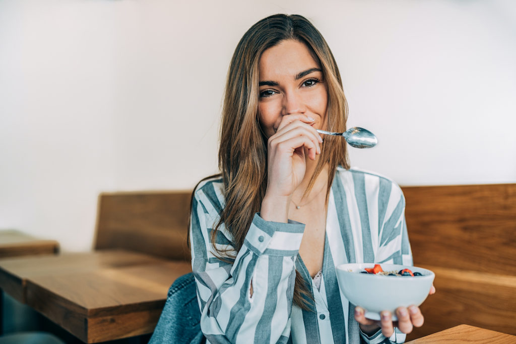 A woman enjoys a light breakfast to not skip meals before the holiday feast, one of the best healthy holiday tips from Super Youth