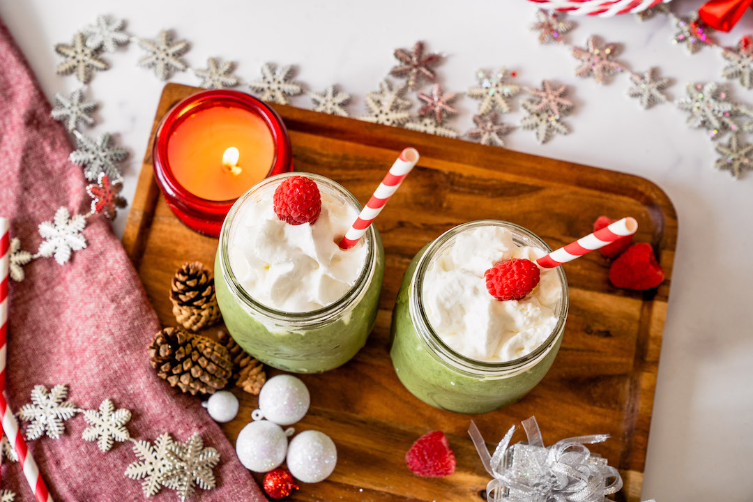 Holiday themed Grinch smoothie with Super Youth Skinny Greens superfood blend on a presentation board.